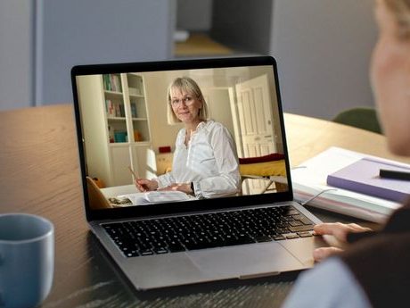Eine blonde Heilpraktikerin sitzt vor einem Laptop und führt einen Videoanruf im Dreiländereck.